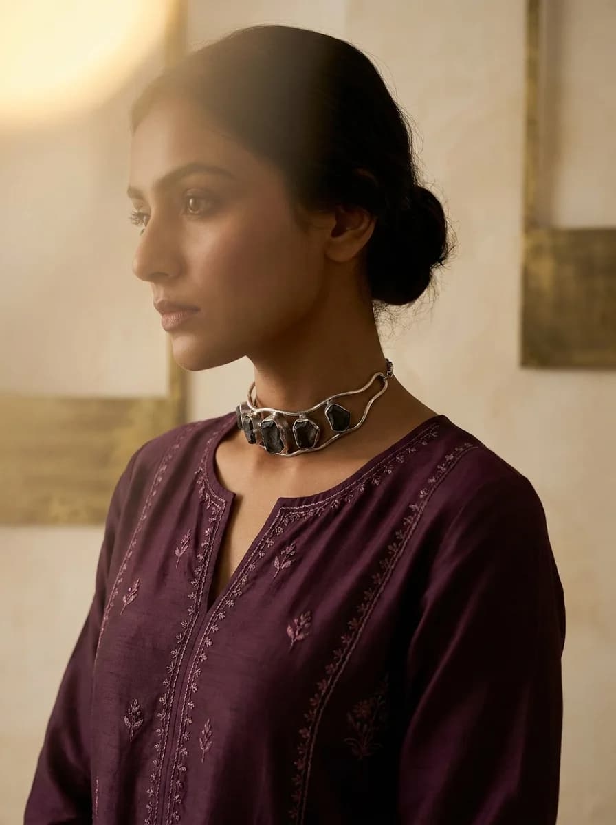 Woman in a plum evening kurta wearing a sculptural silver-tone choker in dusk light